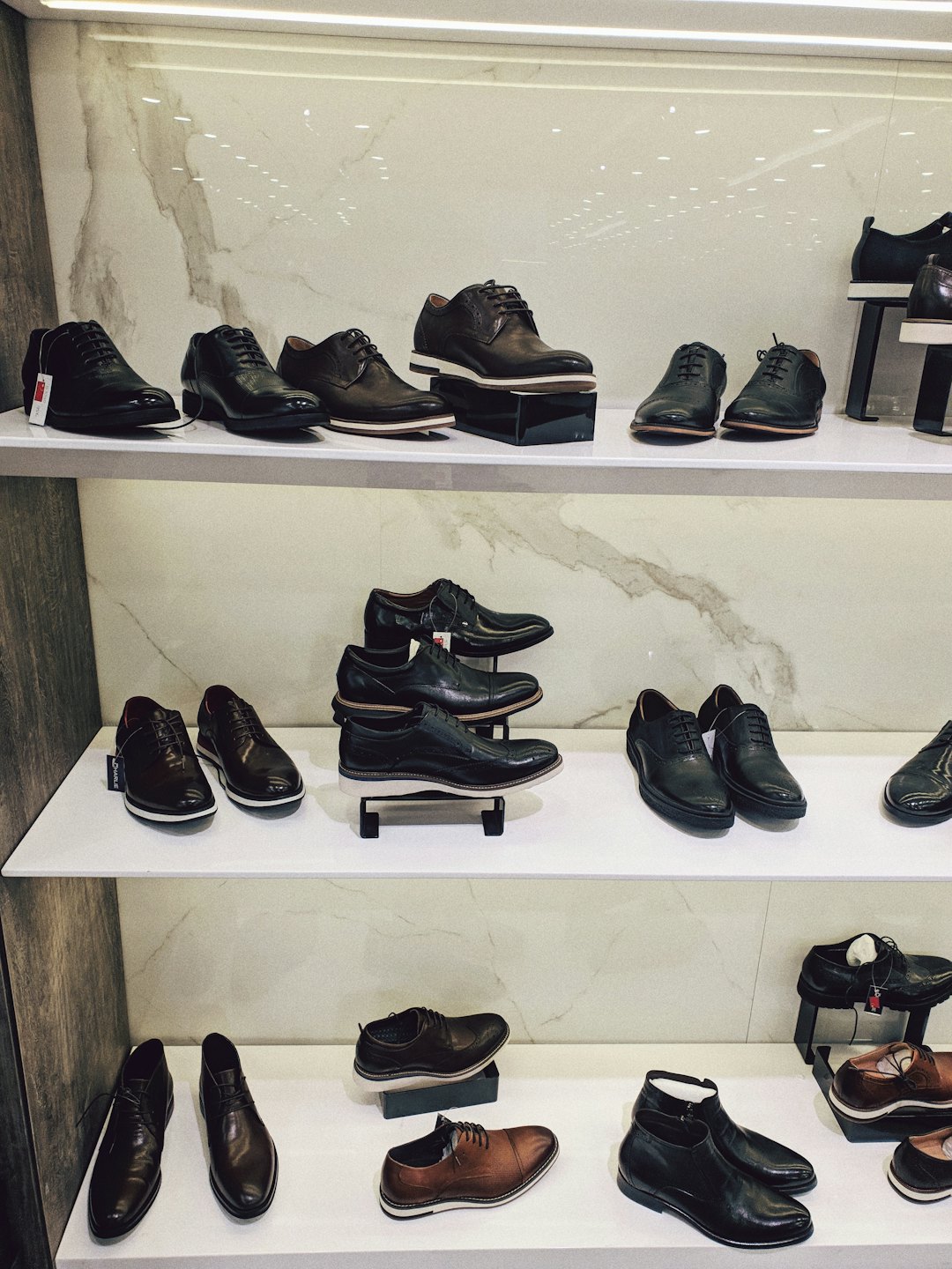 Men's leather dress shoes on white shelves.